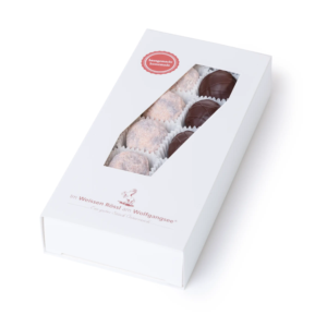 Schlichte, weiße Schachtel mit Sichtfenster, gefüllt mit bunten Schokoladentrüffeln in verschiedenen Farbtönen.