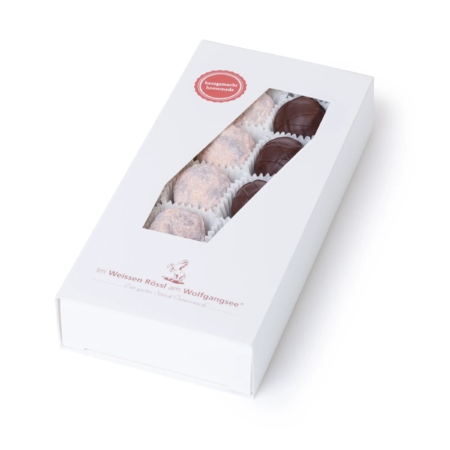 Schlichte, weiße Schachtel mit Sichtfenster, gefüllt mit bunten Schokoladentrüffeln in verschiedenen Farbtönen.